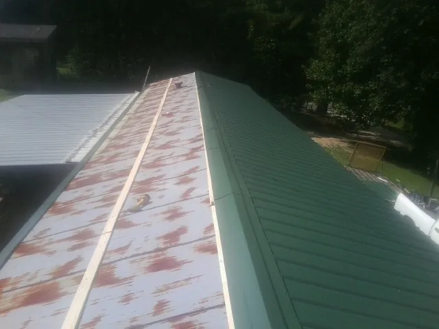Old rusted panels beside newly installed green metal roofing — Wind Damage Roof Repair by Roofing Brothers in Decatur
