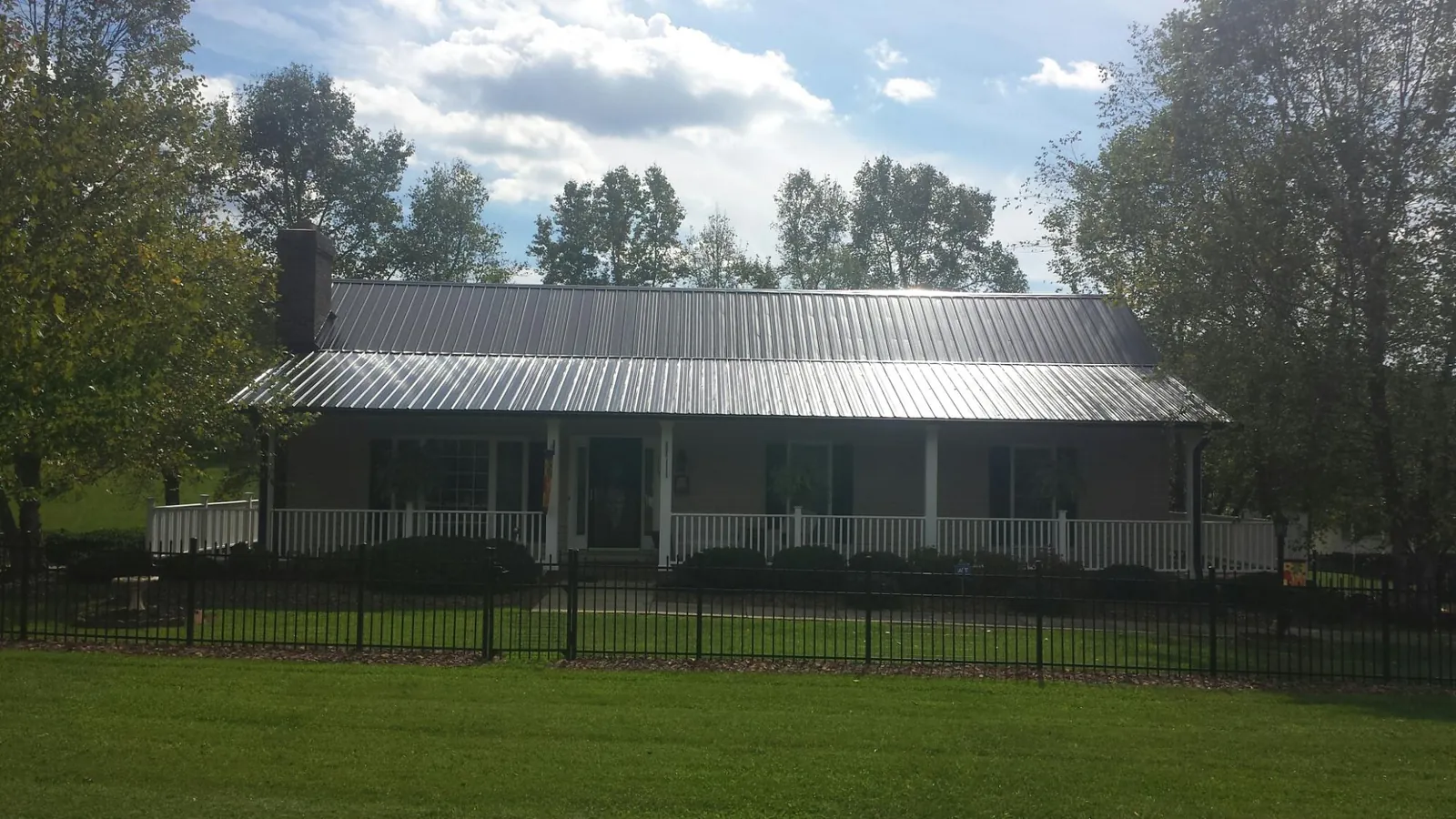 Gray metal roof on a brick ranch with a full width front porch — Gutter Guard Installation work by our crew in Decatur